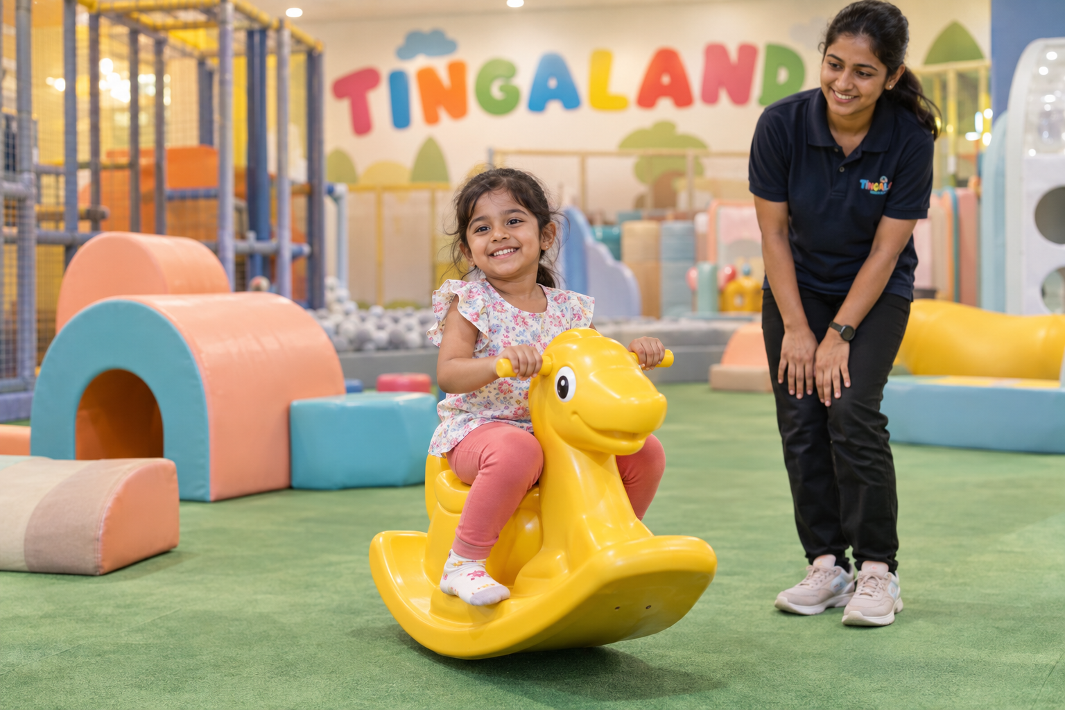 Child balancing on the rocking ride with a Tingaland play attendant nearby